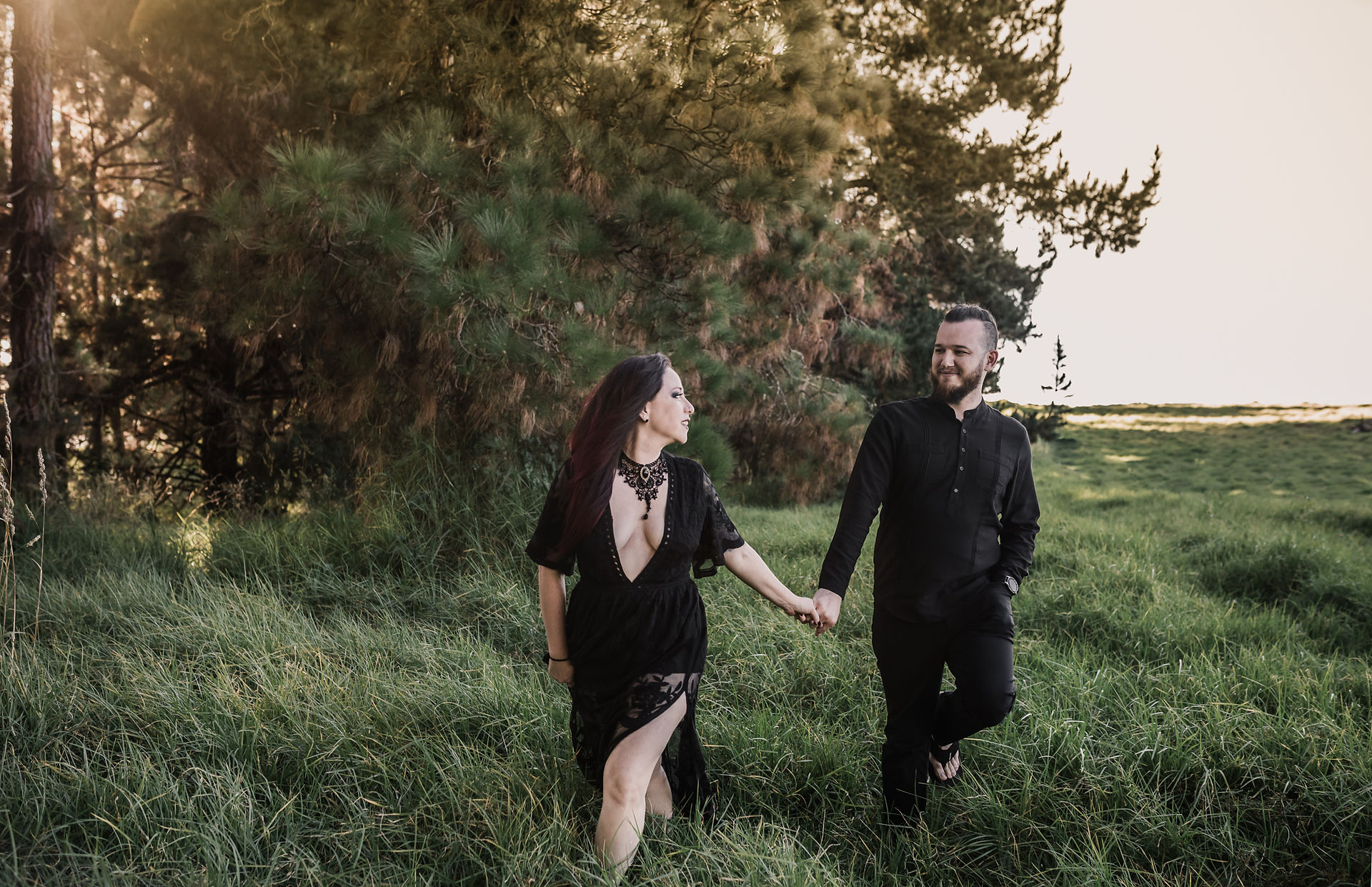 Couple walking hand in hand in the fields looking at each other