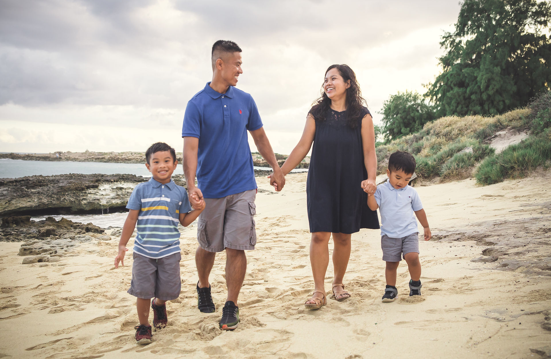 Family of four holding hands walking on the sand