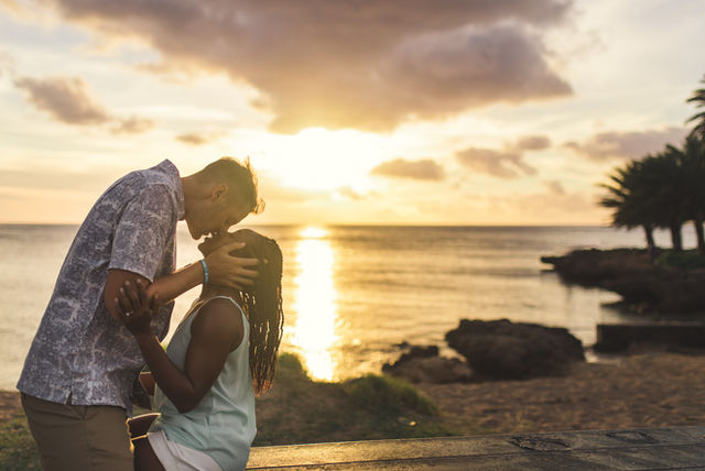 Girlfriend sitting on bench while boyfriend frames her face
