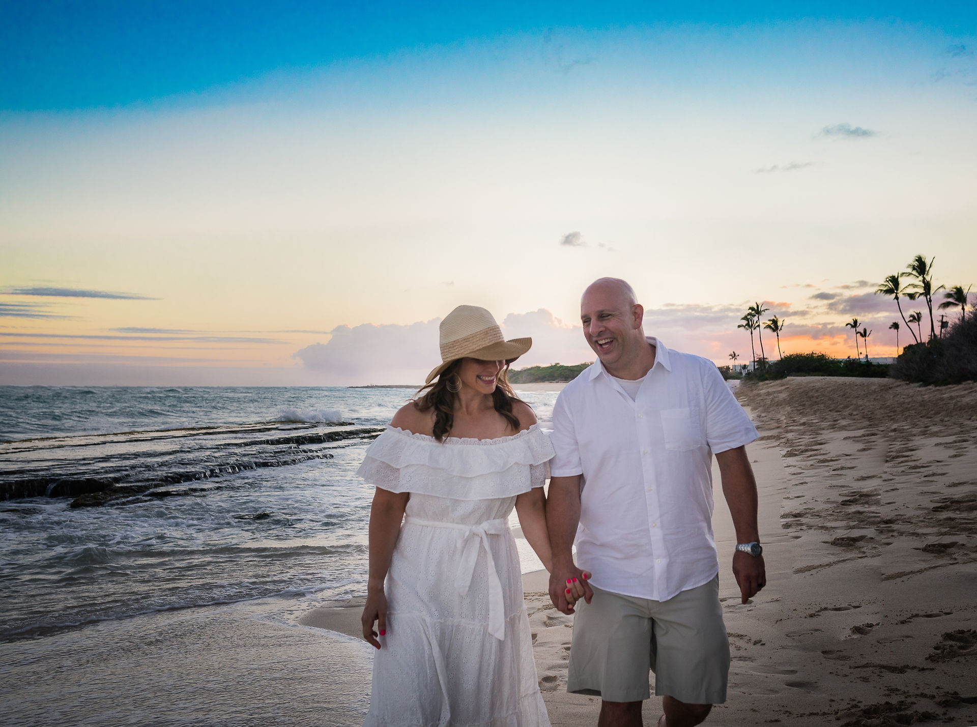 Mom and dad holding hands walking along the beach