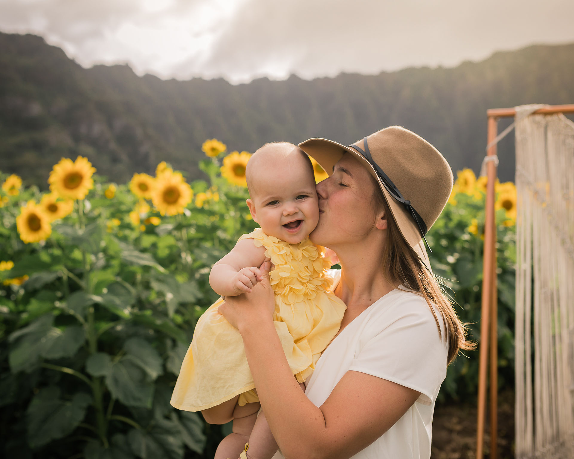 Mom kissing daughter on the cheek while daughter smiles for the camera
