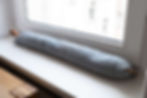 A draft blocker placed in front of a window to stop hot and cold drafts.