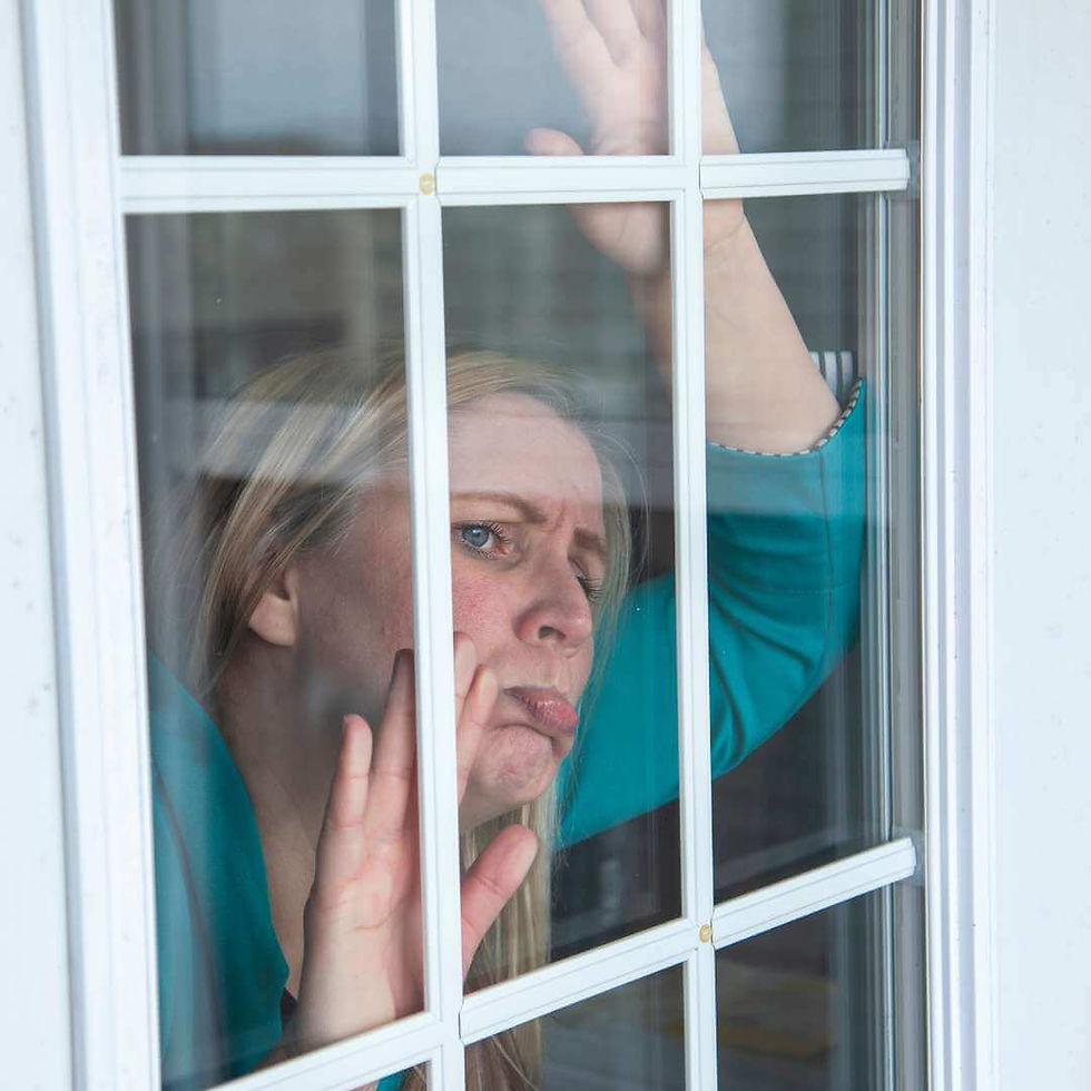 An unhappy woman looks out of her hard-to-open window.