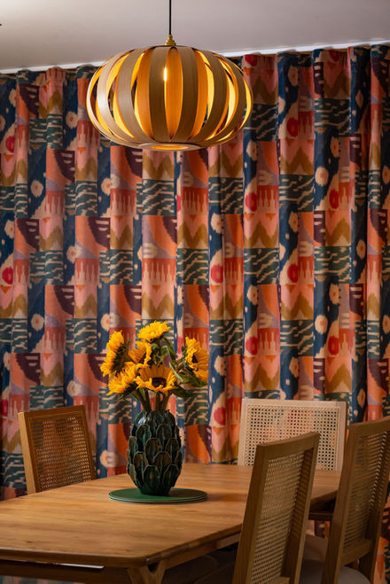 Eclectic dining room with patterned curtains and cane-back dining chairs in Southampton home by interior designer Leisha Norman