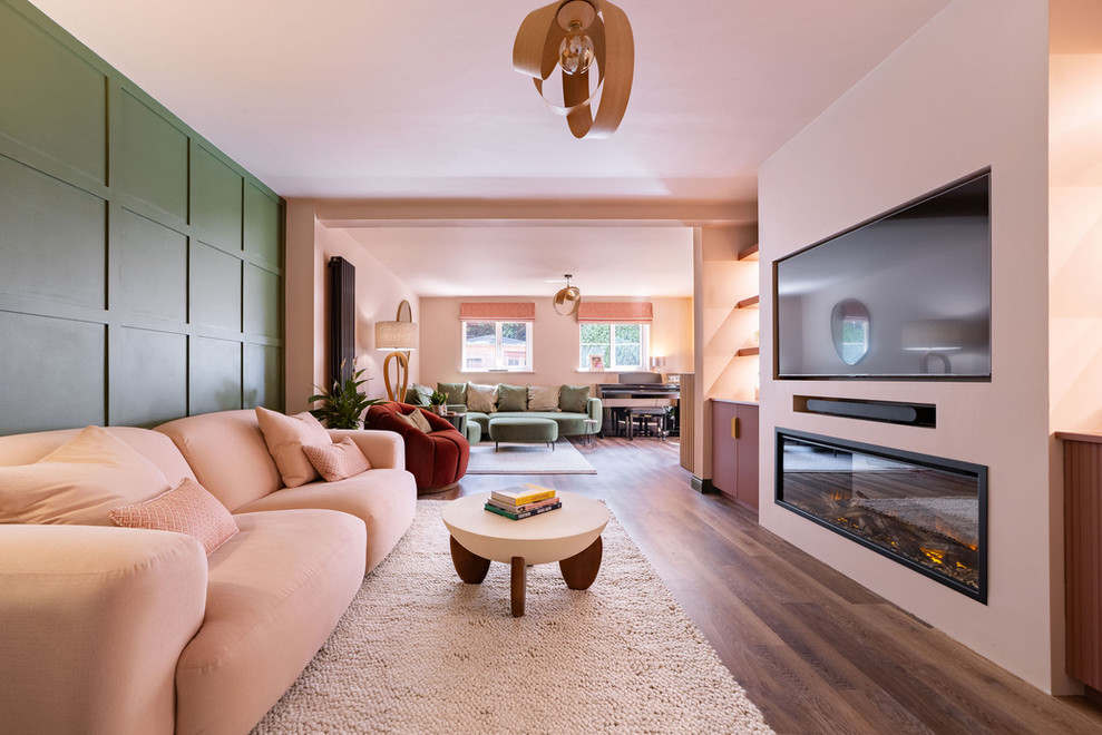 Open-plan living room with blush sofas and full sage green panelled wall in Hampshire