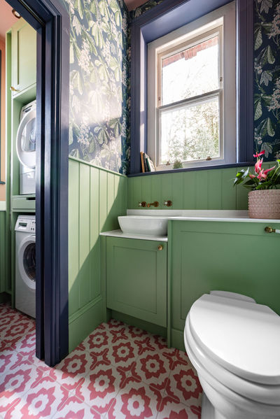 Open green utility room shelves styled with baskets, ceramics and colourful accessories.