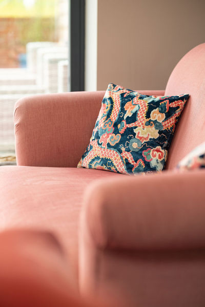 Textured boho cushions in tribal patterns styled on a blush pink sofa, in a cosy, light-filled living room.