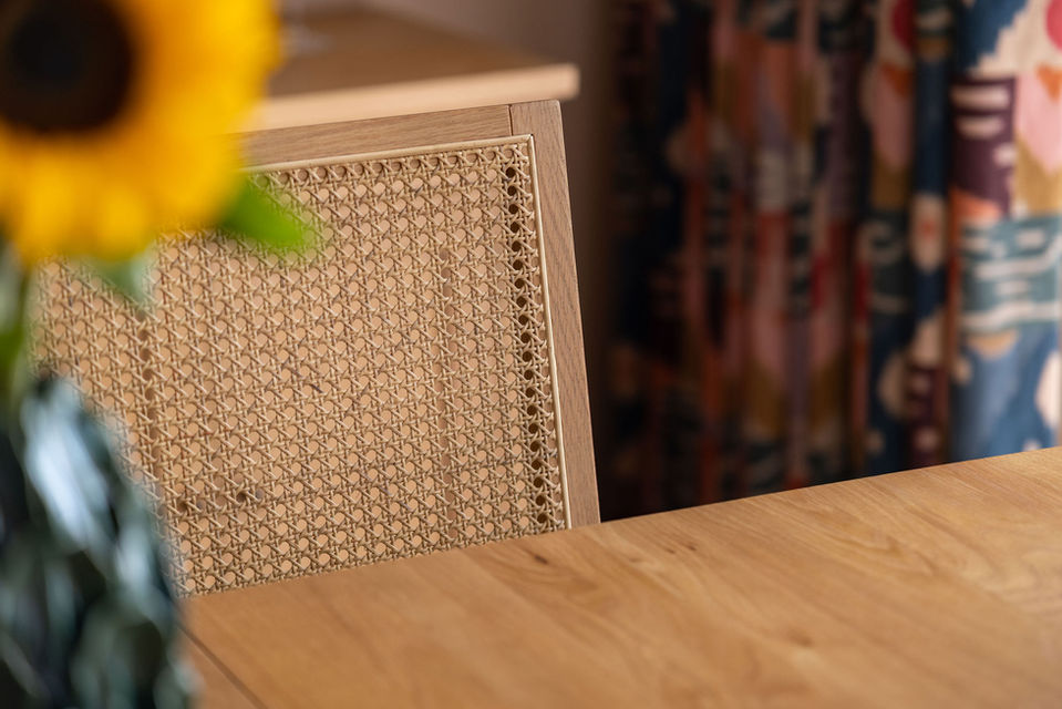Southampton dining room with statement patterned curtains, cane-back chairs and contemporary wood pendant light.