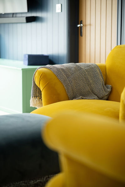 Close-up of mustard velvet armchair with herringbone throw, adding warmth to this playful and practical space.