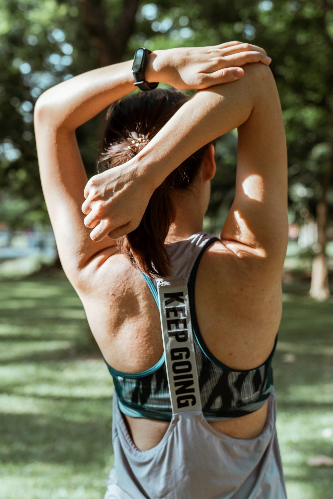 Woman in sport clothes showing her back whilst streching her arms