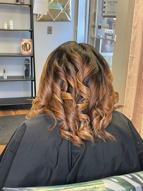 Custom Hair Color & Silk press with smooth. Back view of shoulder-length copper and caramel highlights styled in curls shoulder-length finish on natural hair