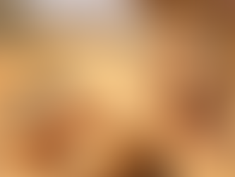 A boy lies face-down in the sand, while a smiling girl holds a stuffed animal beside a camel in a sunny desert landscape.