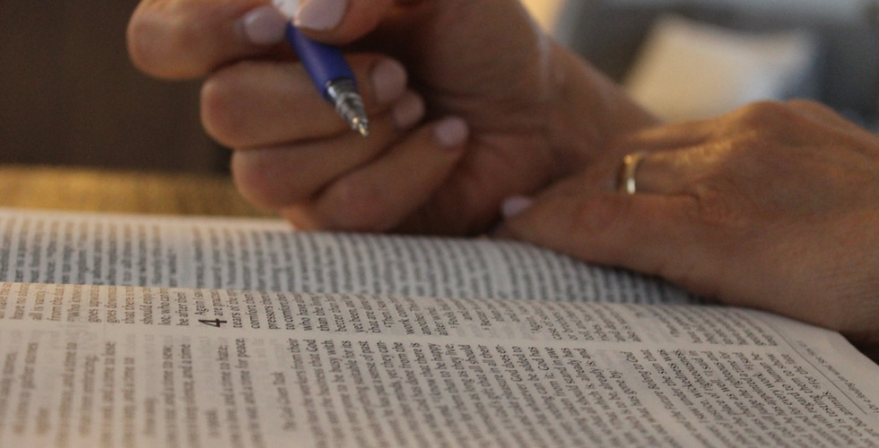 Reading a Bible and underlining words, hands with a pen over the open book