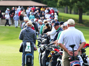 Busy golf course tee area with multiple groups waiting, showing high demand and full tee sheet conditions
