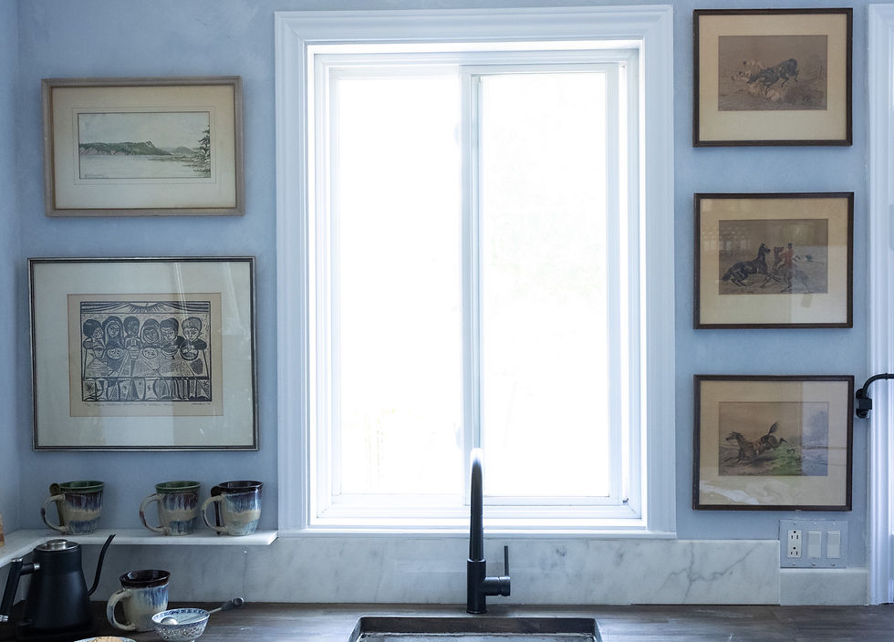 Walnut coloured butcher block counters, marble shelves and backsplash, undermount sink with black faucet. Art hung on periwinkle walls