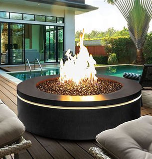 Black circular fire pit with bright flames, fire glass, by pool.
