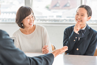 担当講師と話をする女子学生と保護者