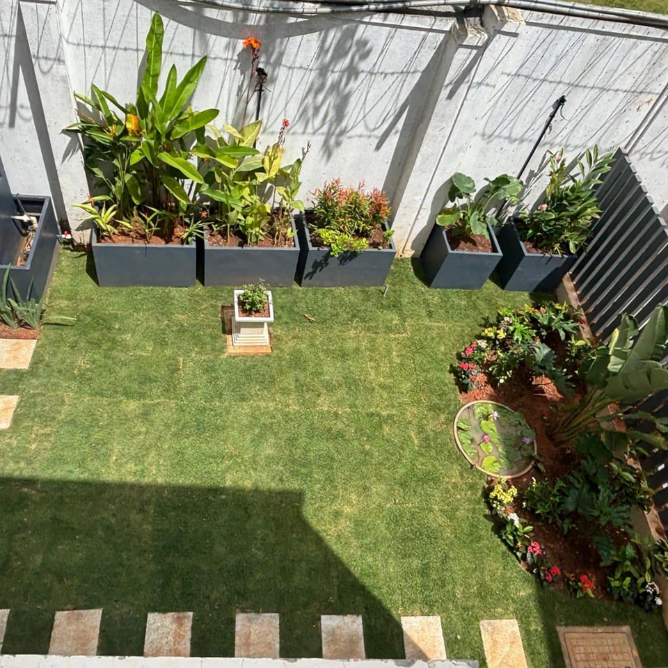 Green lawn with various plants and flower boxes in the yard Anantha Landscape