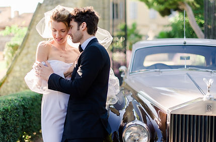 photographe mariage charente maritime - couple enlacé en robe et costume devant l'entrée d'un château provencal proche d'une Rolls Royce beige et brune à La Rochelle en Charente-Maritime