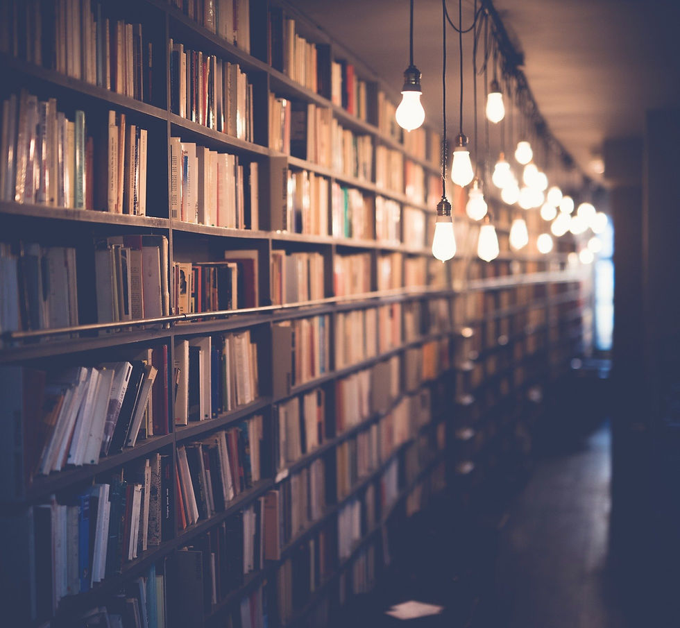 Books stacked on a bookcase with dim lights hanging from ceiling.