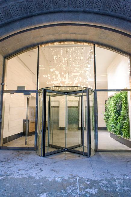 Black and wood reception desk with marble walls illuminated by Bocci lighting in New York office