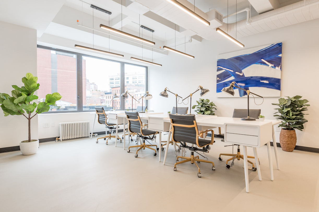 Open workspace with white desks and large windows overlooking Chelsea at 80 Eighth Avenue office renovation