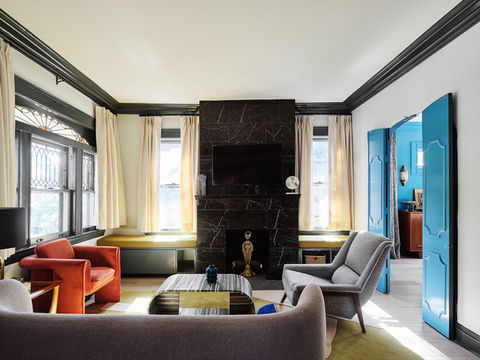Elegant living space with mid-century furniture and vintage fireplace in restored Victorian home