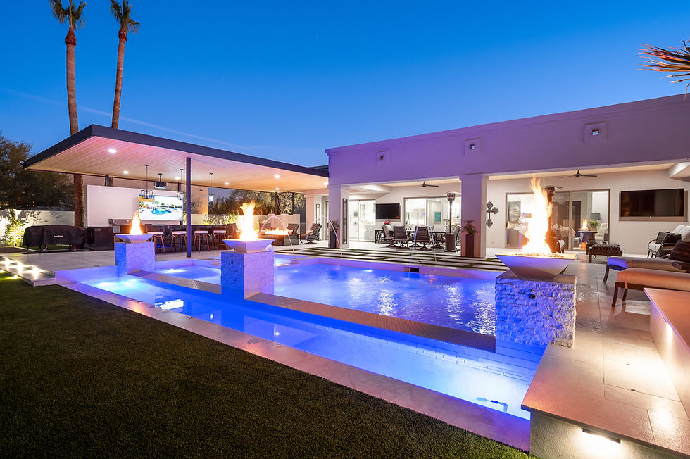 Luxurious outdoor pool area illuminated by vibrant blue lighting and accentuated with dramatic fire features, creating an inviting nighttime oasis.