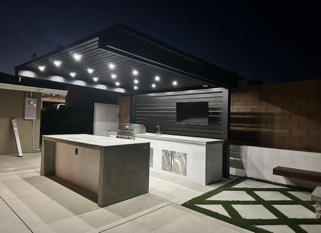 Modern cantilever pergola with integrated lighting, showcasing a sleek outdoor kitchen setup at night.