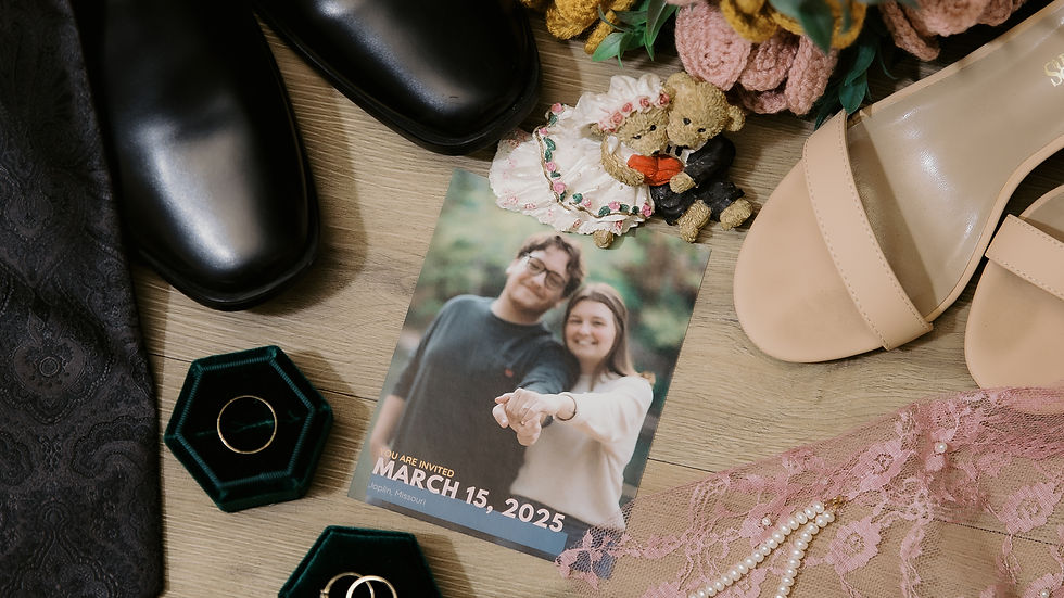 Wedding items on wood: black shoes, tie, bouquet, rings, pink lace, pearls, photo with "March 15, 2025" invite, beige heels. Romantic vibe.