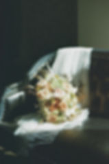 Bouquet of pastel roses on a studded black leather couch with white fabric, softly lit, conveying an elegant, serene mood.