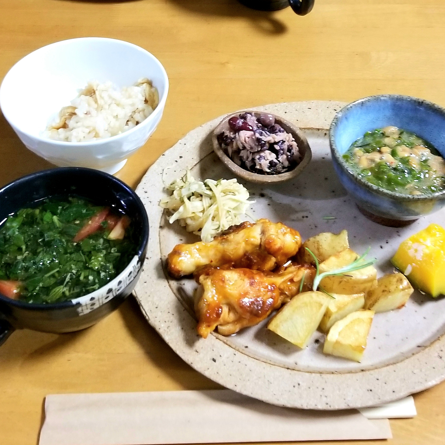 白飯と汁物、野菜、魚介や肉の料理が並ぶ家庭的な食卓。