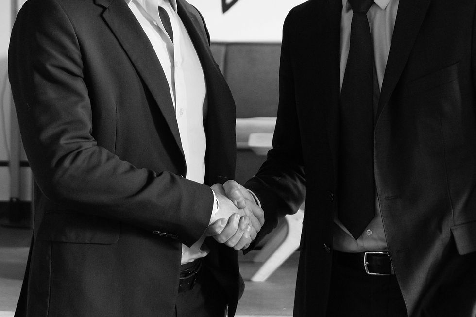 two business people shaking hands. Photo is in black and white.
