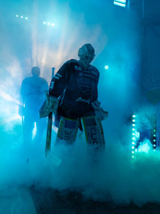 Ice hockey goalie entering the rink through smoke and lights