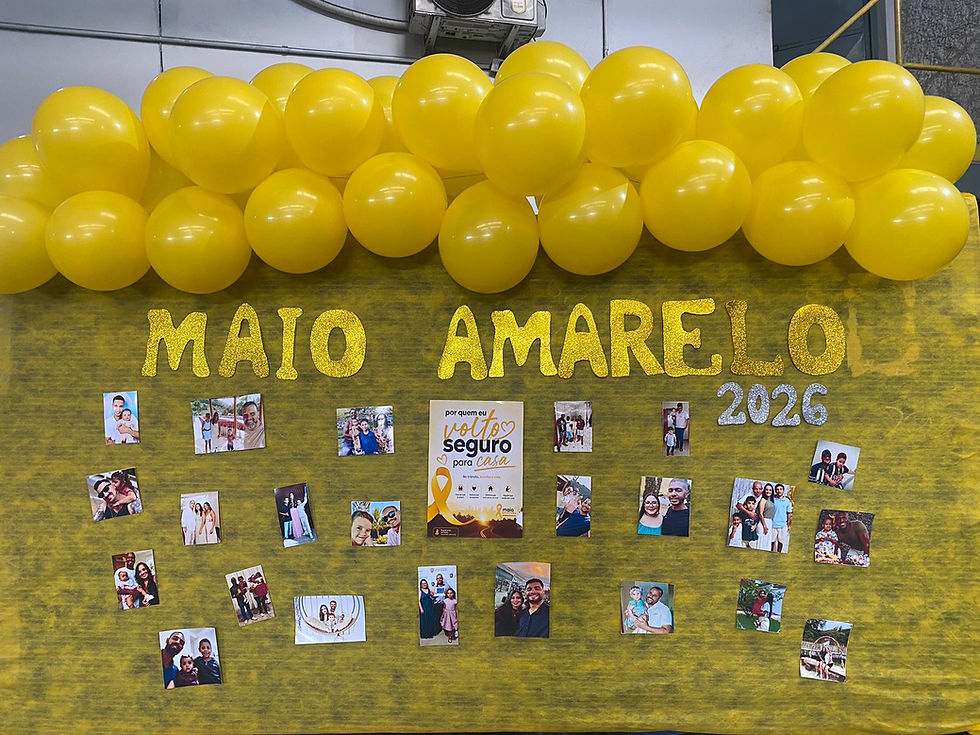 Painel com balões amarelos, fotos de famílias e cartaz, com texto Maio Amarelo 2026 e mensagem de trânsito seguro.