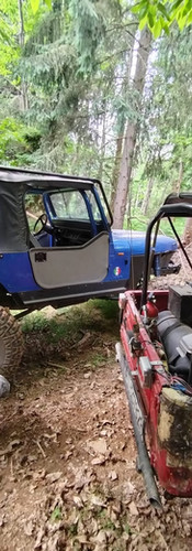 Jeep blu elettrico e Suzuki rosso parcheggiate nel bosco