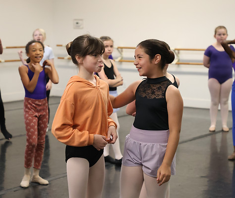 Dancers in a musical theater dance class making silly faces and smiling at one another