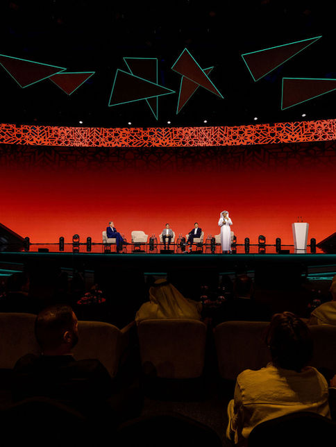 Wide view of a red-lit stage with geometric ceiling lights at a corporate awards gala