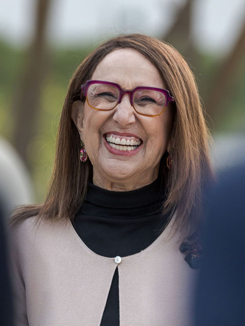 Close up of a woman with glasses smiling broadly at an outdoor event