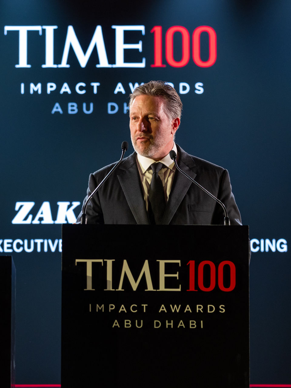Zak Brown, CEO of McLaren Racing, delivering a keynote speech at a prestigious TIME100 Impact Awards podium, photographed by a London VIP event photographer.