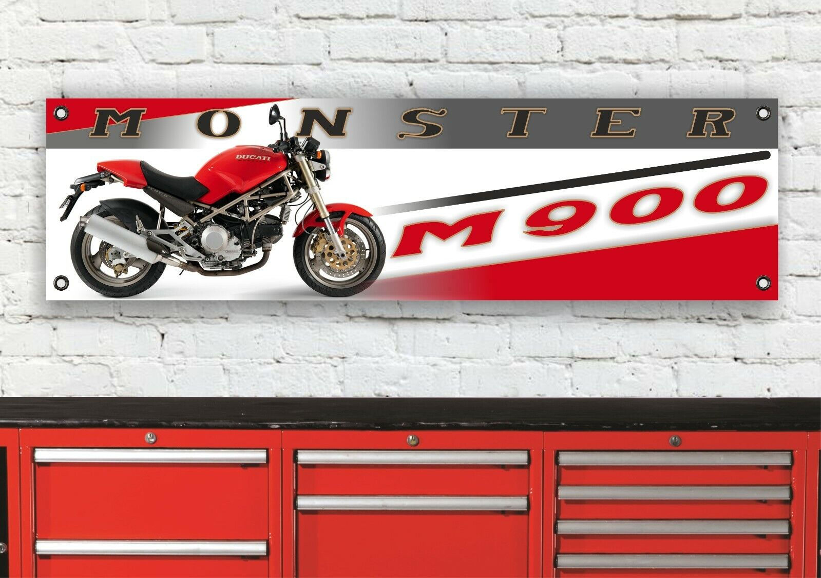Red Ducati Monster M900 motorcycle displayed on a banner over red cabinets.