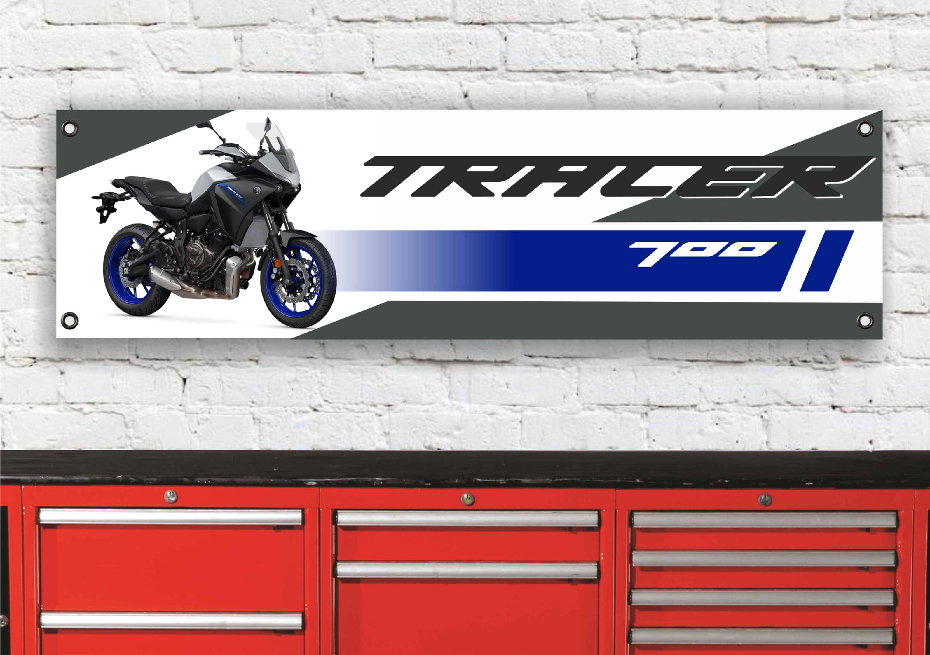 Motorcycle banner with text TRACER 700 and bike image on a wall backdrop.