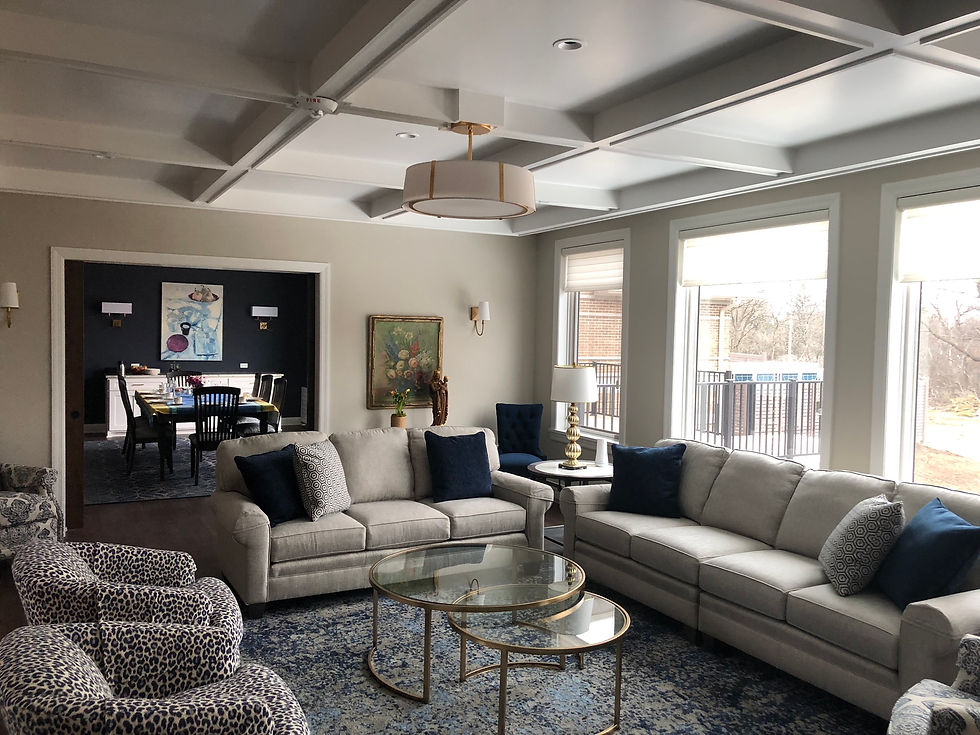 Together, the architecture and interior design unite to create a comfortable place under a coffered ceiling with furniture and an area rug. Artwork and light fixtures are also interior design choices.