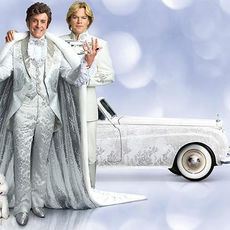 A dazzling figure in ornate costume stands beside a young man at his side—an image of brilliance and intimacy.