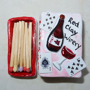 A handmade oven-bake clay matchbox featuring a hand-painted wine-inspired design on the lid. The functional piece includes a strike strip along one side so it can be used like a traditional matchbox, combining whimsical craftsmanship with everyday utility in a thoughtful handmade birthday gift.