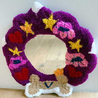 A colorful handmade tufted wall piece created as a Mother’s Day gift, featuring a mirror installed at the center for the artist’s mother’s dog, Violet. Soft, sculptural yarn designs surround the mirror, transforming it into a playful and functional piece of art for both people and pets.