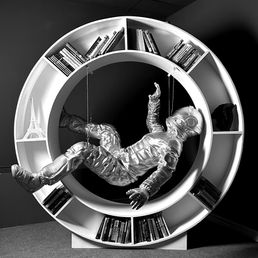 Handmade functional sculpture bookshelf inspired by space exploration, featuring a floating astronaut within a circular bookshelf.