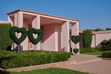 pink-house-mid-century-vintage-columns-hollywood-regency-heart-hedges.jpg