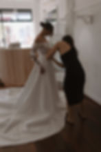 Thumbnail: Designer Sally Victoria fitting the overskirt on the Sabrina wedding gown, captured from a side view during bridal styling.