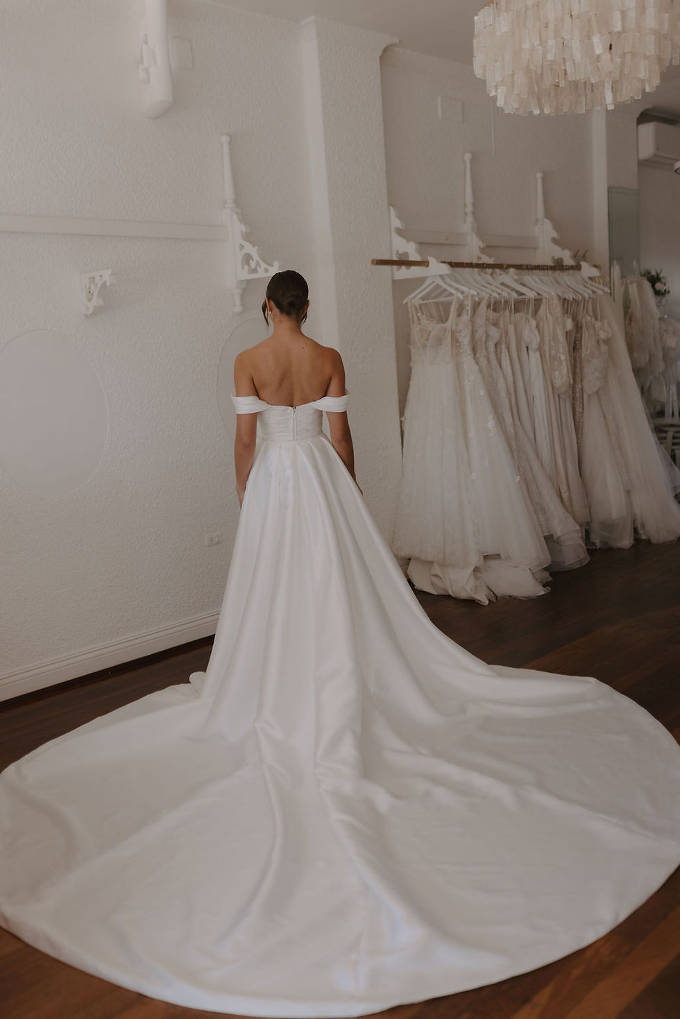 Thumbnail: Back full-length view of Sierra wedding dress with overskirt and train, showing detachable off-shoulder sleeves.